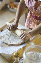 Mixed race woman rolling dough on cutting board
