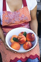 Mixed race woman holding bowl of peaches