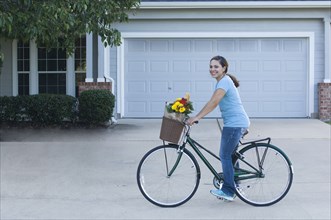 Mixed race woman riding bicycle in driveway