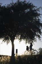 Silhouette of mixed race woman with bicycle in park