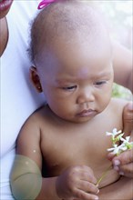 Mixed race baby holding flowers