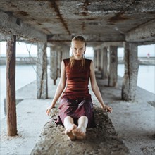 Caucasian girl wearing wet dress sitting underneath dock
