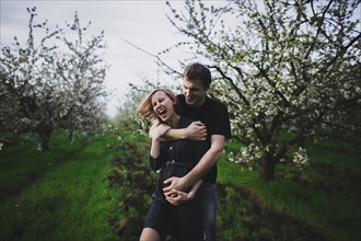Caucasian couple hugging near trees