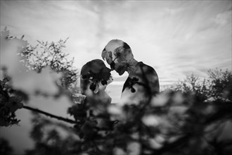 Double exposure of Caucasian couple kissing near trees