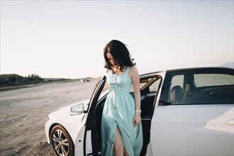 Caucasian woman standing near open car door