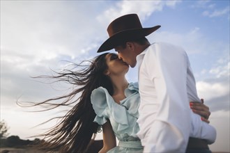 Caucasian cowboy kissing woman in wind