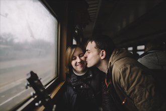 Caucasian man kissing woman on cheek in train
