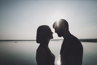 Silhouette of smiling Caucasian couple at lake