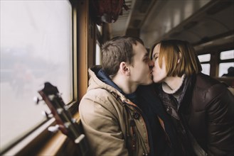 Caucasian couple kissing on train