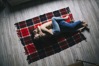 Caucasian couple laying on plaid blanket and hugging