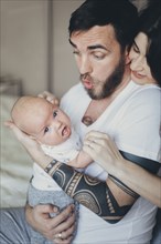 Caucasian mother and father playing with baby son