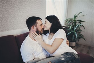 Caucasian couple cuddling and kissing on sofa