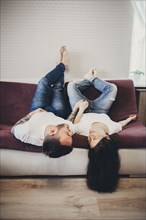 Caucasian couple laying upside-down on sofa