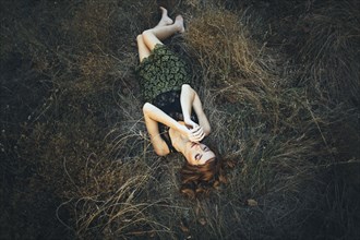 Pensive Caucasian woman laying on grass