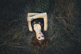 Serious Caucasian woman laying on grass
