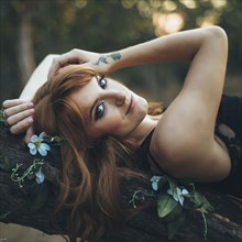 Smiling Caucasian woman laying on tree branch