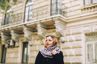 Portrait of serious Caucasian woman wearing scarf near building