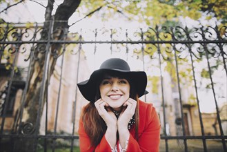 Portrait of smiling Caucasian woman wearing hat near fence