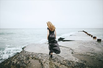 Portrait of Caucasian woman wearing dress walking near ocean