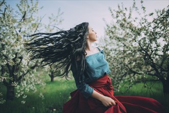 Caucasian woman tossing hair near flowering trees