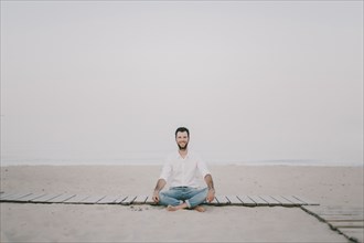 Caucasian man sitting on boardwalk at beach