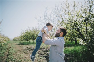 Caucasian father lifting son near tree