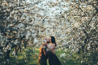 Caucasian couple kissing near blooming trees