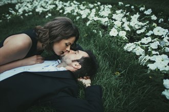 Caucasian couple laying in grass kissing