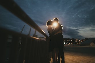 Caucasian couple kissing near railing at night