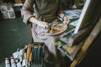 Caucasian woman squeezing paint onto palette