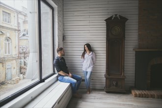 Caucasian couple hanging out near window