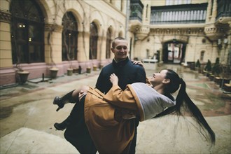 Caucasian man lifting and carrying woman in courtyard
