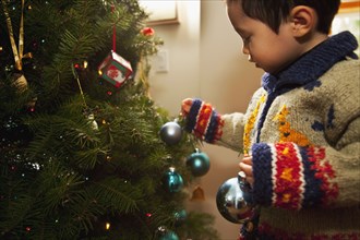 Mixed race boy decorating Christmas tree