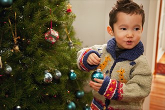 Mixed race boy decorating Christmas tree