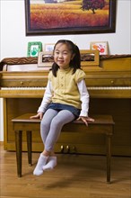 Korean girl sitting on piano bench