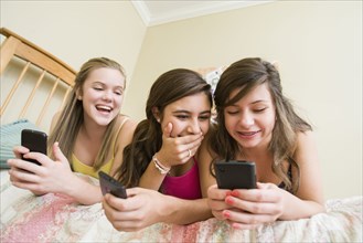 Caucasian teenage girls text messaging on cell phone