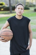 Mixed race boy holding basketball