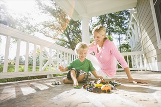 Caucasian mother and son playing with toys on porch