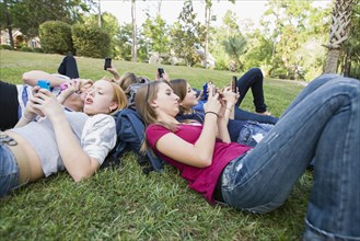 Friends hanging out together on grass using cell phones