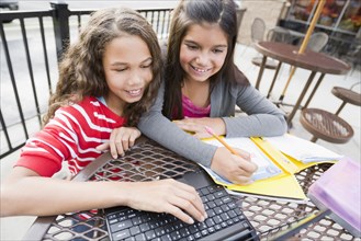 Smiling girls using laptop at cafe
