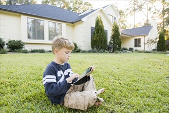 Caucasian boy using digital tablet on lawn