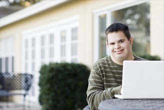 Disabled Caucasian man using laptop outdoors