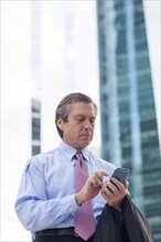 Caucasian businessman using cell phone outside highrise