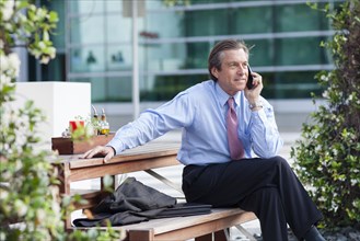 Caucasian businessman on cell phone on picnic bench