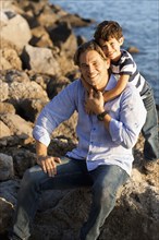 Caucasian father and son hugging on rocky beach