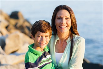 Caucasian mother and son smiling on rocky beach