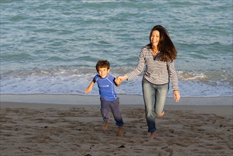 Caucasian mother and son playing on beach