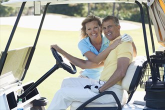 Caucasian couple hugging in golf cart on course