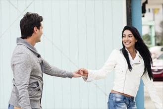 Hispanic couple holding hands outdoors