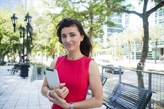 Caucasian businesswoman carrying digital tablet in urban park